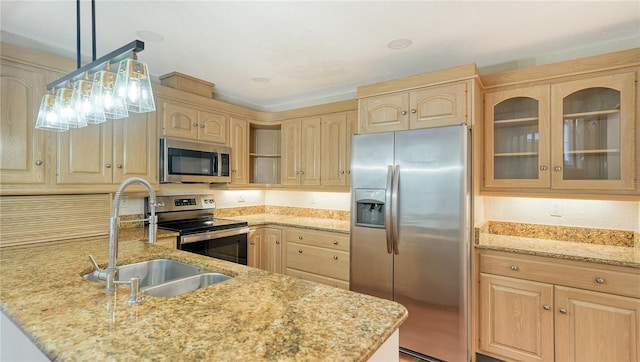 kitchen with light stone countertops, appliances with stainless steel finishes, light brown cabinetry, sink, and hanging light fixtures