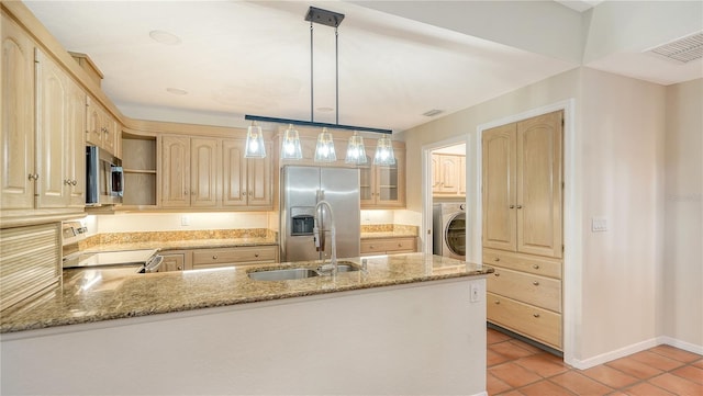 kitchen with stainless steel appliances, kitchen peninsula, decorative light fixtures, washer / dryer, and light brown cabinetry