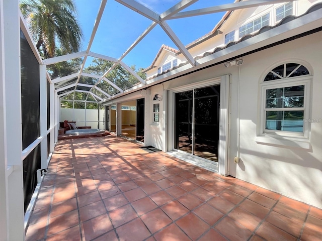 view of patio featuring glass enclosure and a hot tub