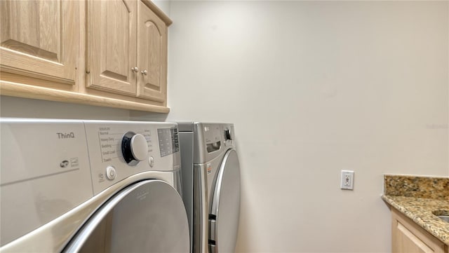 washroom featuring cabinets and washer and clothes dryer