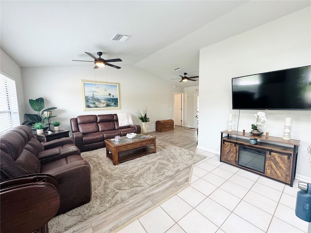 living area with lofted ceiling, ceiling fan, light tile patterned flooring, visible vents, and baseboards