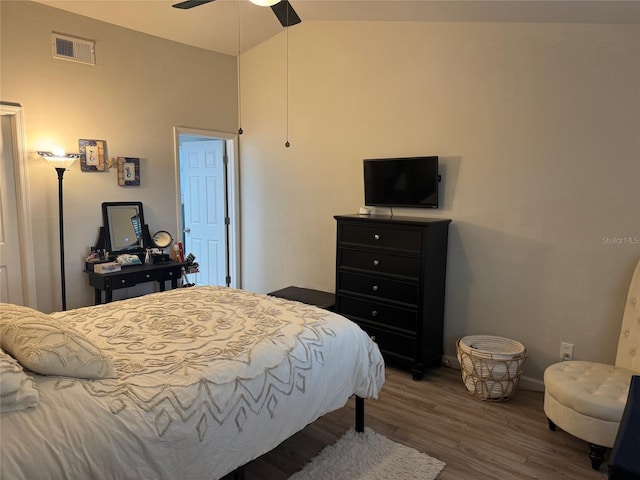 bedroom with baseboards, visible vents, ceiling fan, wood finished floors, and vaulted ceiling