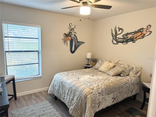 bedroom with ceiling fan, multiple windows, baseboards, and wood finished floors