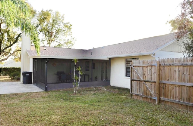 rear view of property with a yard, a shingled roof, fence, and a sunroom