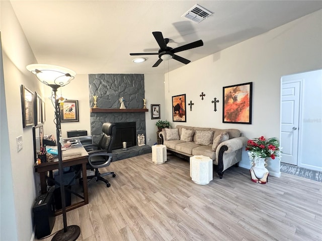 home office featuring a ceiling fan, visible vents, a fireplace, and light wood-style flooring