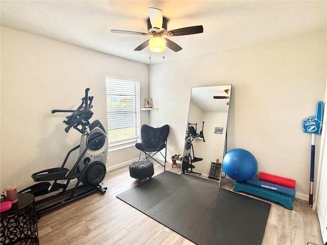 workout room with wood finished floors, a ceiling fan, and baseboards