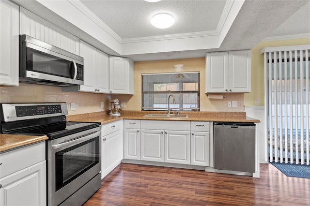 kitchen with sink, appliances with stainless steel finishes, a textured ceiling, white cabinets, and ornamental molding