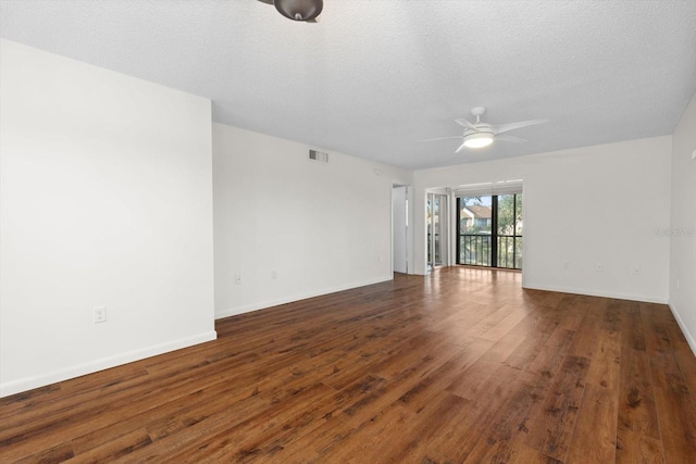 empty room with a textured ceiling, dark hardwood / wood-style floors, and ceiling fan