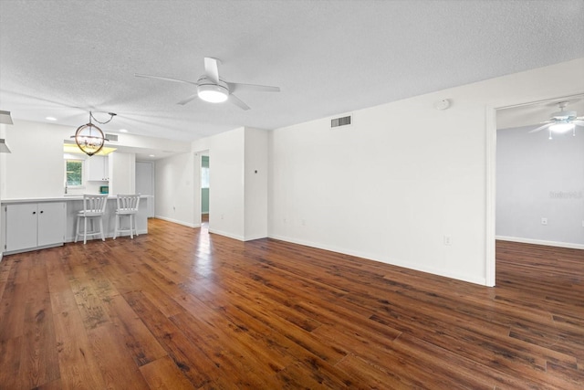 unfurnished living room with hardwood / wood-style floors, ceiling fan with notable chandelier, and a textured ceiling