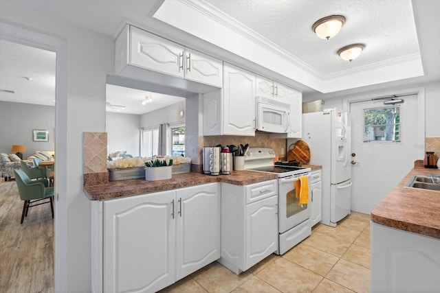 kitchen featuring white appliances, light tile patterned floors, a textured ceiling, tasteful backsplash, and white cabinetry