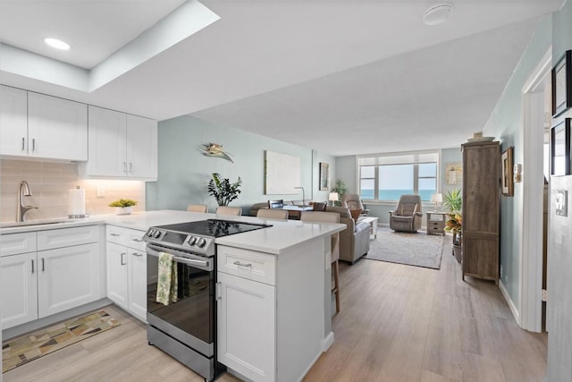 kitchen with light hardwood / wood-style floors, white cabinetry, and stainless steel electric range