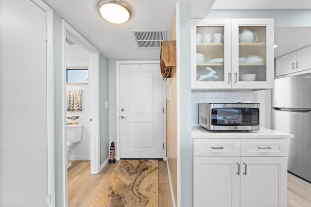 kitchen with light wood-type flooring, white cabinetry, and appliances with stainless steel finishes