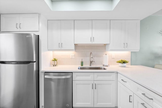 kitchen featuring white cabinets, backsplash, stainless steel appliances, and sink