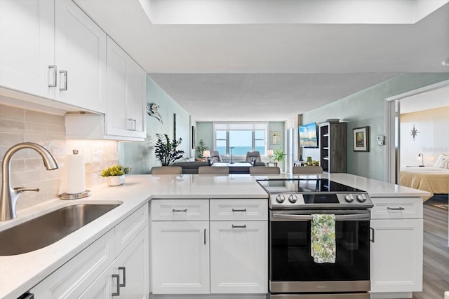 kitchen featuring hardwood / wood-style flooring, white cabinetry, electric stove, and sink