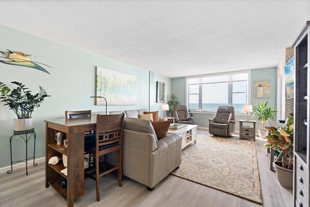 living room featuring a textured ceiling, light hardwood / wood-style floors, and a water view