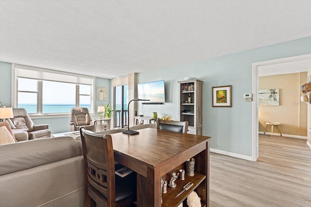 dining area with light hardwood / wood-style floors and a textured ceiling