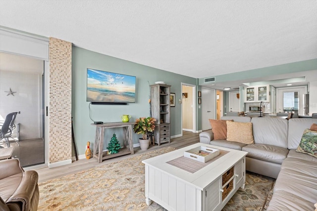 living room with a textured ceiling and light wood-type flooring