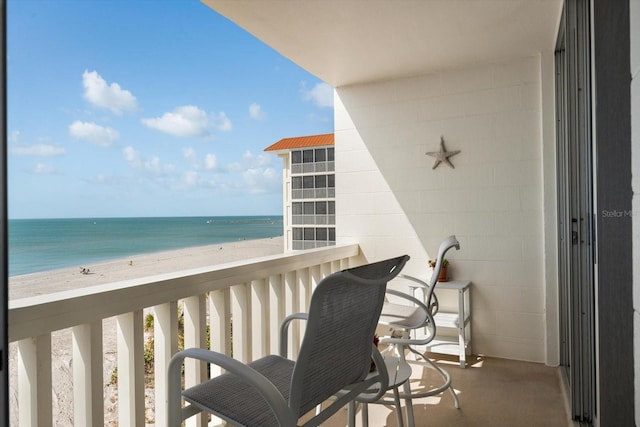 balcony with a water view and a view of the beach