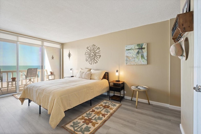 bedroom featuring hardwood / wood-style flooring, a water view, and a textured ceiling