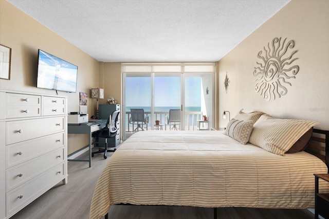 bedroom with a textured ceiling, access to outside, and light hardwood / wood-style floors