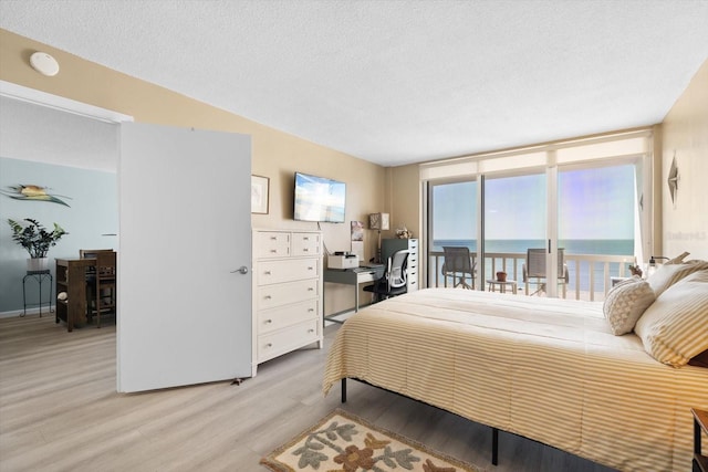 bedroom featuring light hardwood / wood-style floors, a textured ceiling, and access to outside