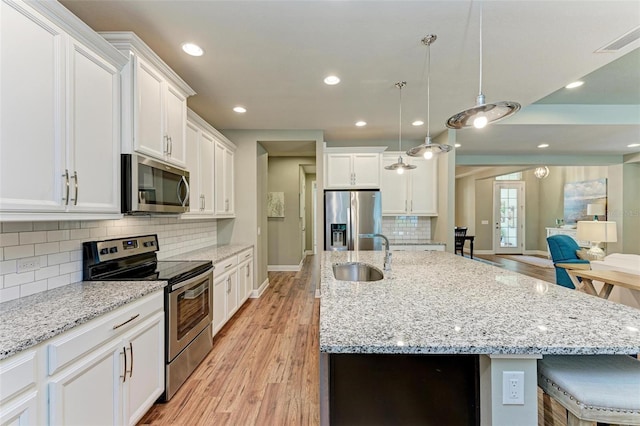 kitchen with decorative light fixtures, white cabinetry, sink, and appliances with stainless steel finishes