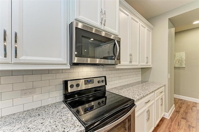 kitchen featuring light stone countertops, light wood-type flooring, tasteful backsplash, electric stove, and white cabinets