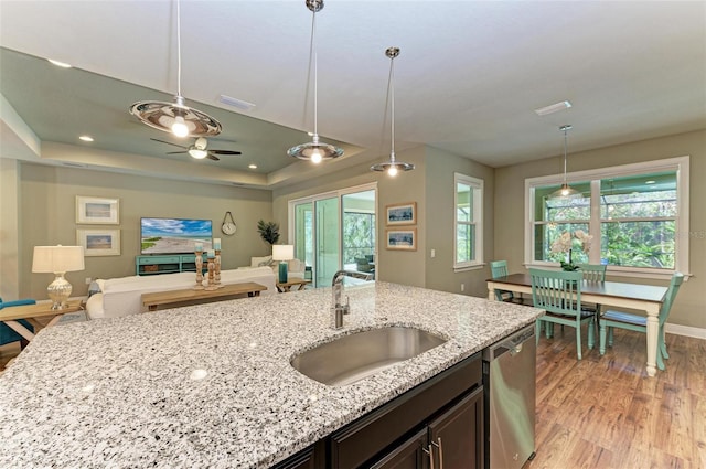 kitchen featuring light stone counters, stainless steel dishwasher, hanging light fixtures, and sink