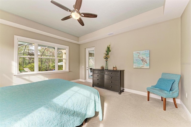 bedroom featuring ceiling fan, a raised ceiling, and light carpet