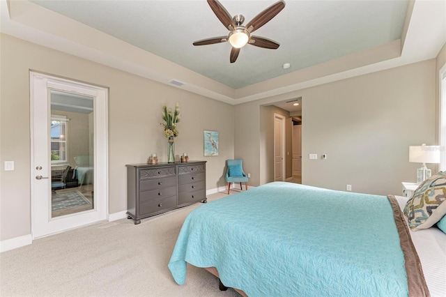 carpeted bedroom featuring a raised ceiling and ceiling fan