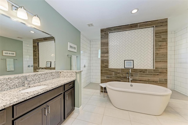 bathroom featuring a tub to relax in, tile patterned floors, vanity, and tile walls