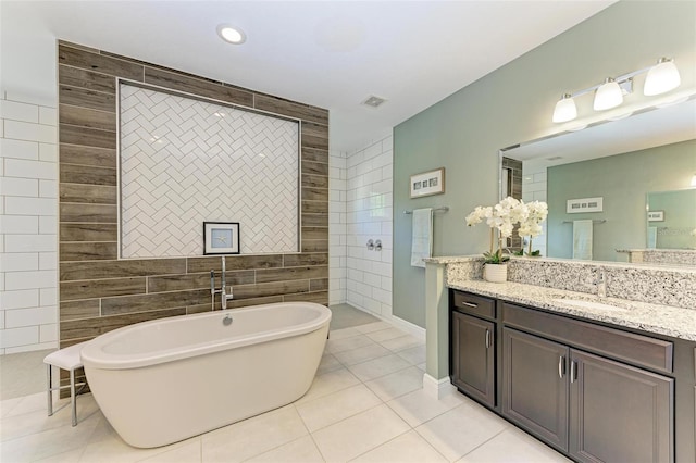 bathroom featuring vanity, tile patterned floors, tile walls, and a tub