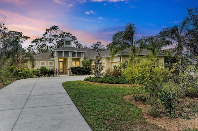 view of front facade featuring a garage, driveway, a front lawn, and stucco siding