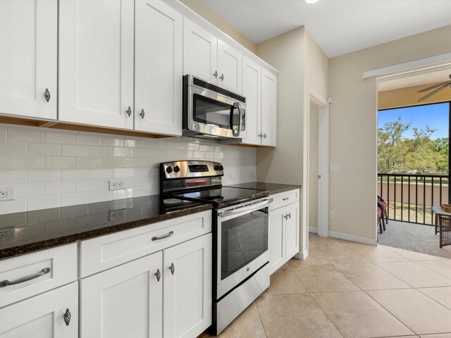 kitchen with light tile patterned floors, dark stone counters, decorative backsplash, white cabinets, and appliances with stainless steel finishes