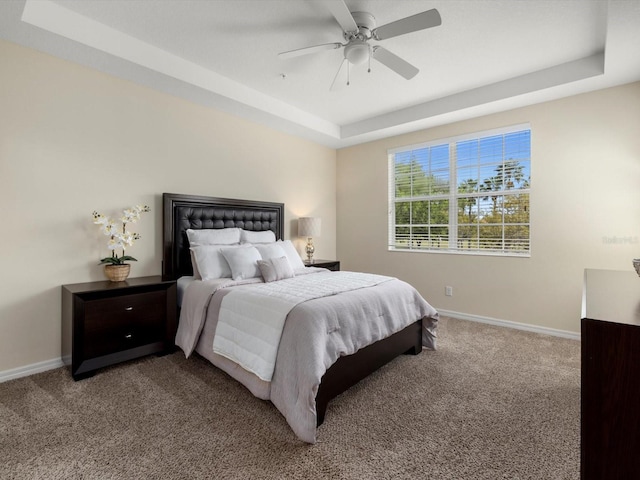 carpeted bedroom with ceiling fan and a raised ceiling