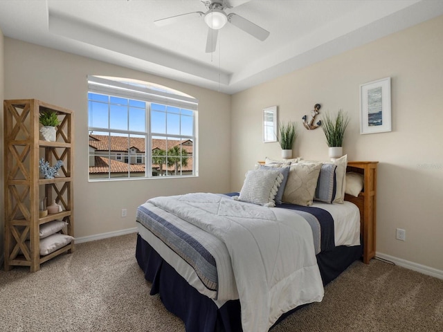 bedroom featuring carpet, a tray ceiling, and ceiling fan