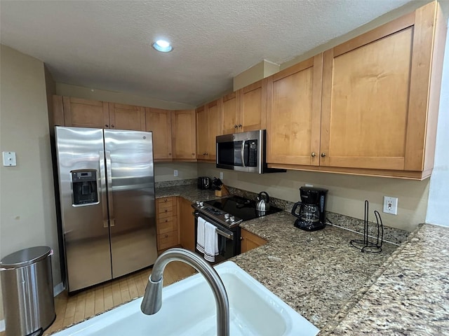 kitchen with appliances with stainless steel finishes, a textured ceiling, and sink