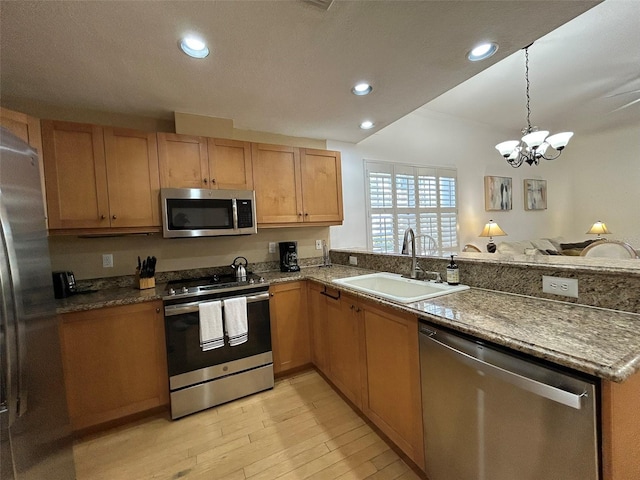 kitchen featuring hanging light fixtures, sink, appliances with stainless steel finishes, a notable chandelier, and light hardwood / wood-style floors