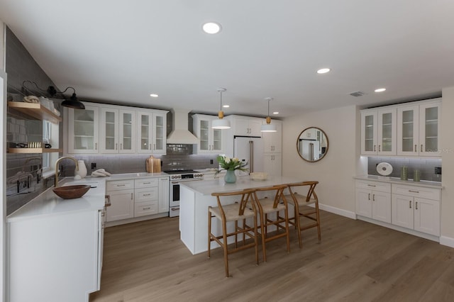 kitchen with white cabinetry, premium range hood, decorative light fixtures, white appliances, and a kitchen island