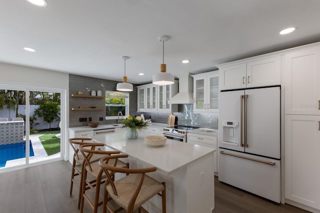 kitchen with white appliances, hanging light fixtures, decorative backsplash, custom range hood, and white cabinetry