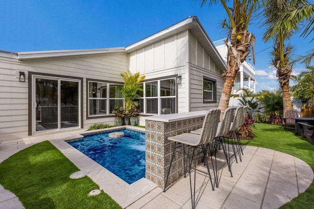 view of swimming pool featuring a lawn, a patio area, and exterior bar