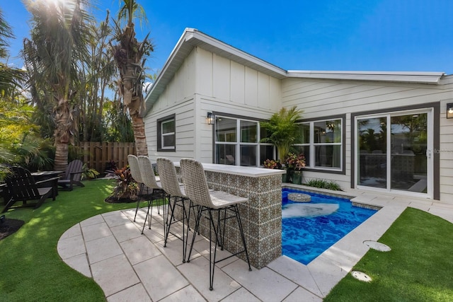 view of swimming pool with exterior bar, a yard, and a patio