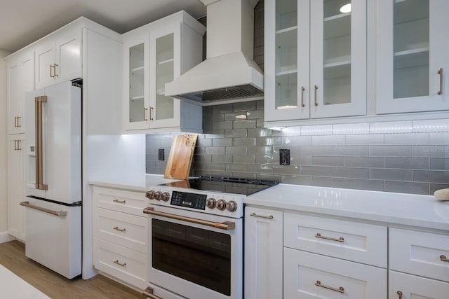 kitchen featuring white cabinetry, electric range, backsplash, high end fridge, and custom exhaust hood