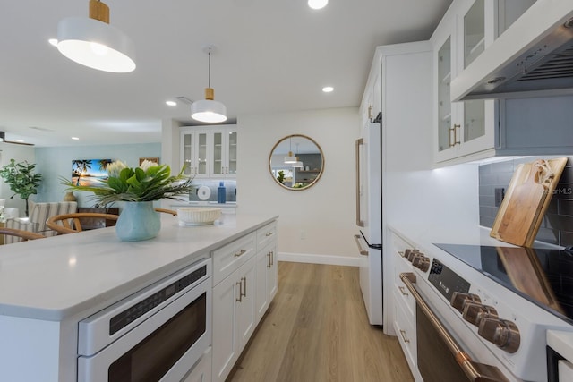 kitchen featuring backsplash, custom range hood, white appliances, white cabinets, and hanging light fixtures