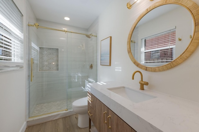 bathroom featuring hardwood / wood-style flooring, vanity, toilet, and a shower with door