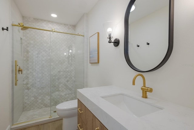 bathroom featuring vanity, toilet, and a shower with shower door