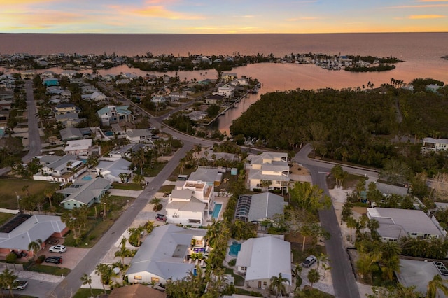 aerial view at dusk featuring a water view