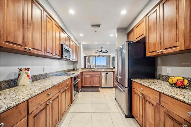 kitchen with light stone countertops, stainless steel appliances, ceiling fan, sink, and light tile patterned floors