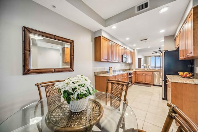 kitchen with light stone countertops, light tile patterned floors, stainless steel appliances, and ceiling fan