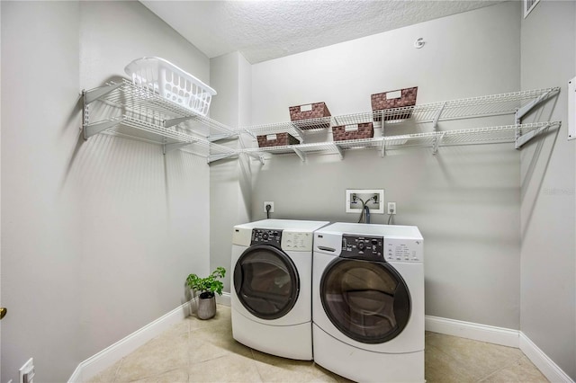 laundry room with light tile patterned flooring, a textured ceiling, and washing machine and clothes dryer